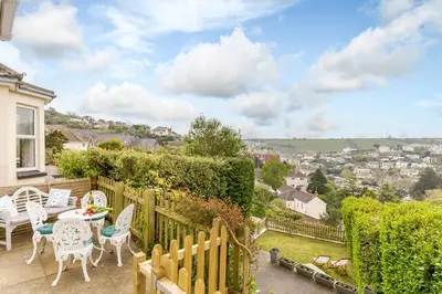a patio with a table and chairs and a fence at Wisteria in St Austell