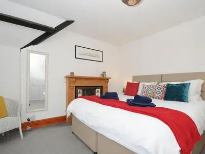 a bedroom with a large bed and a fireplace at Elmbank in Looe