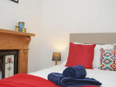 a bed with red and blue towels sitting on it at Elmbank in Looe