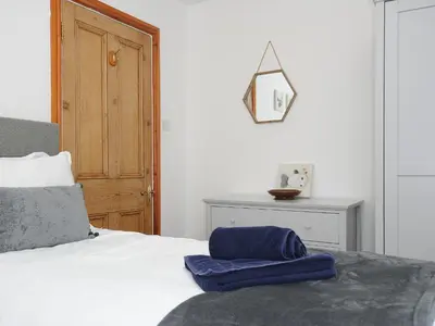a bedroom with a bed with a blue pillow on it at Elmbank in Looe