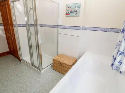 a bathroom with a shower and a bed in a room at Elmbank in Looe