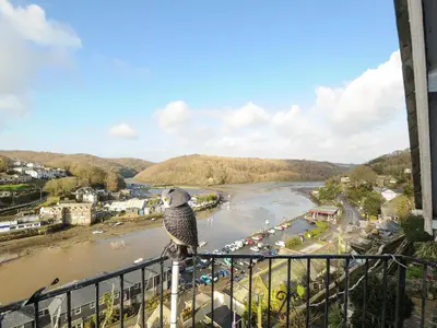 a bird sitting on a railing overlooking a river at Elmbank in Looe