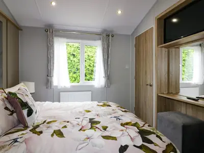 a bedroom with a bed with a floral comforter at Pinehurst Lodge in Redruth