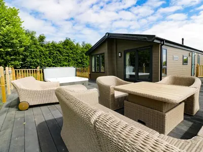 a deck with wicker chairs and a table and a building at Pinehurst Lodge in Redruth