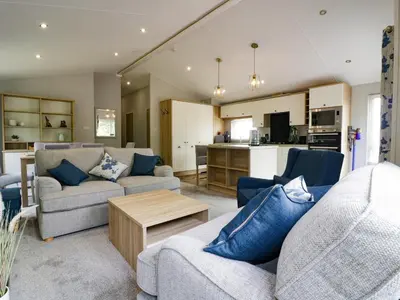 a living room with two couches and a kitchen at Pinehurst Lodge in Redruth