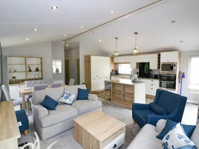 a living room with couches and a kitchen at Pinehurst Lodge in Redruth