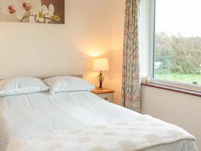 a bedroom with a bed and a window at Little Lanes in Camelford