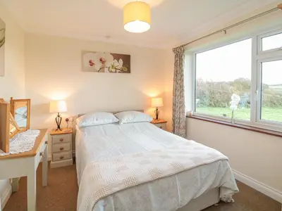 a bedroom with a bed and a desk and a window at Little Lanes in Camelford