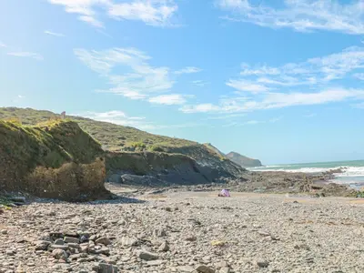 a beach with rocks and a blue sky and clouds at Little Lanes in Camelford