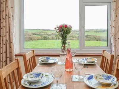 a table with plates and wine glasses and a window at Little Lanes in Camelford