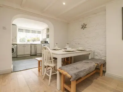 a dining room with a table and chairs and a kitchen at Riversdale Cottage in Wadebridge
