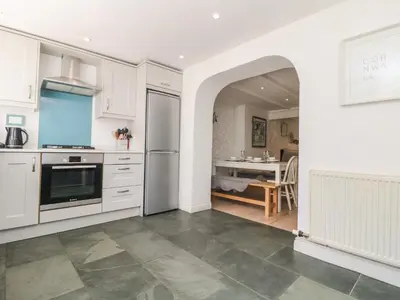 a kitchen with a stainless steel refrigerator and a table at Riversdale Cottage in Wadebridge