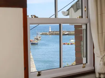 a window view of a harbor with boats in the water at Polkirt Forge in Mevagissey
