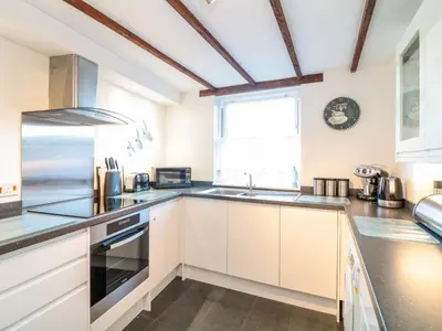 a kitchen with white cabinets and a window at Polkirt Forge in Mevagissey