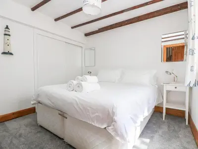 a white bedroom with a large bed and a window at Polkirt Forge in Mevagissey