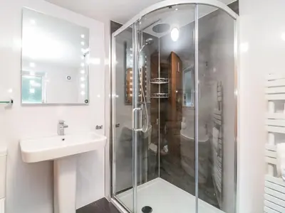 a white bathroom with a shower and a sink at Polkirt Forge in Mevagissey