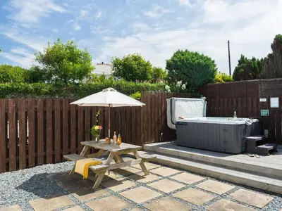 a picnic table with an umbrella and a hot tub at Karrek in Tintagel