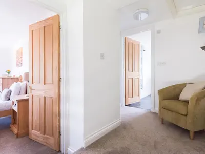 a living room with a chair and a bedroom at Karrek in Tintagel