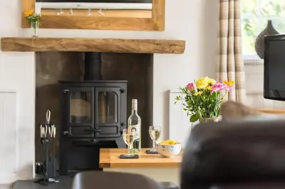 a living room with a stove with two glasses of wine at Karrek in Tintagel