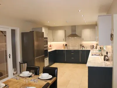a kitchen with a table and chairs and a refrigerator at Atlantic Reach in Bude