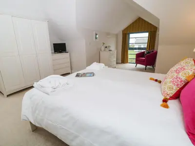 a bedroom with a white bed and a red chair at Atlantic Reach in Bude