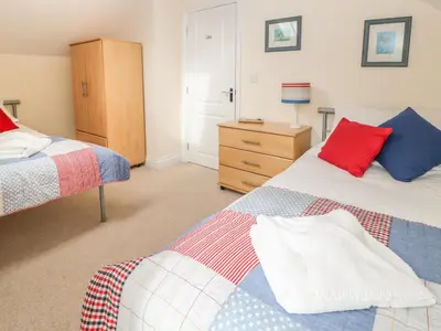 a bedroom with two beds and a dresser at Atlantic Reach in Bude