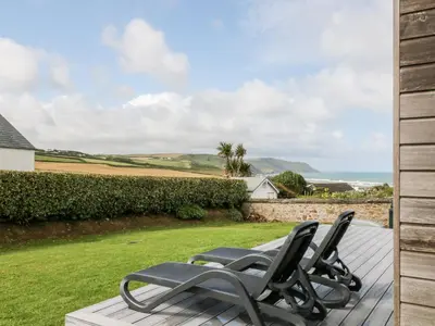 three chairs sitting on a deck with a view of the ocean at Atlantic Reach in Bude