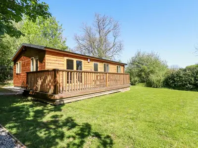 a log cabin in a yard with a large lawn at Lodge One in Truro