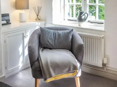 a chair with a pillow in a room with a window at 3 Rose Cottages in St. Agnes