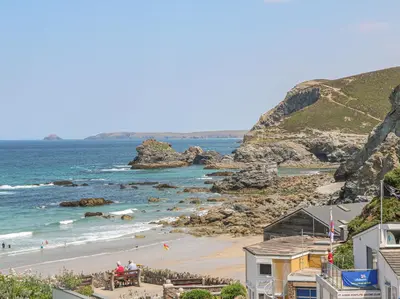 a view of a beach with people sitting on a bench at 3 Rose Cottages in St. Agnes