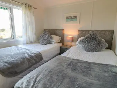 two beds in a room with a window at Smugglers Shack in Polperro