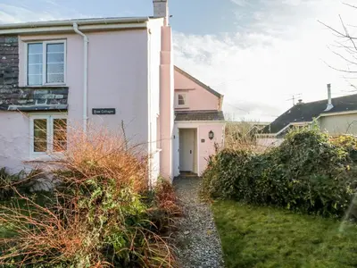 a white house with a door and a yard at 1 Rose Cottages in Looe