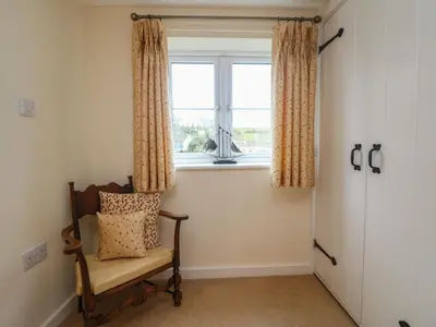 a room with a chair and a window at 1 Rose Cottages in Looe