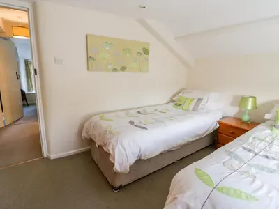 a bedroom with two beds and a painting on the wall at 3 Rose Cottages in Looe