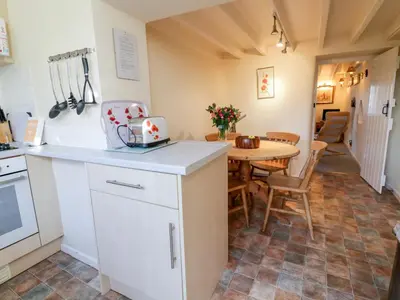 a kitchen and dining room with a table with a laptop at 3 Rose Cottages in Looe