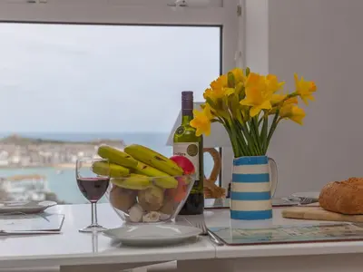 a table with a bottle of wine and a vase of flowers at Trevose in St Ives