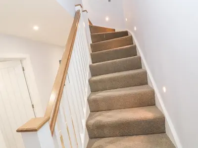 a staircase in a home with white walls and white carpet at Driftwood Haven in St Ives