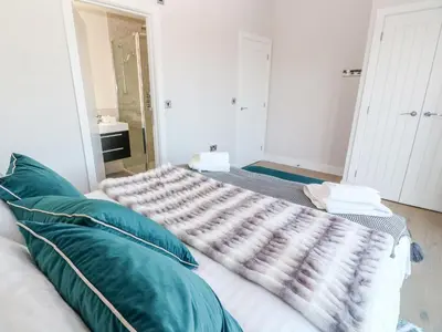 a bedroom with a bed with green pillows at Driftwood Haven in St Ives