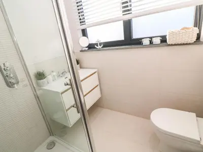 a bathroom with a shower and a toilet and a window at Driftwood Haven in St Ives