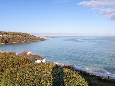 a house on a hill next to the ocean at Driftwood Haven in St Ives