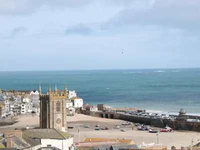 a city with a clock tower next to a beach at Driftwood Haven in St Ives