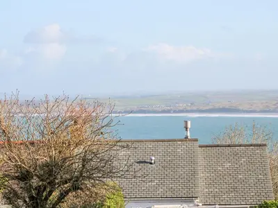 a view of the ocean from a house with a brick wall at Driftwood Haven in St Ives