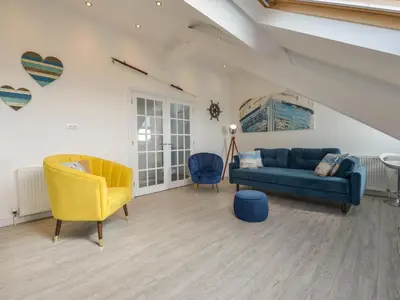 a living room with a blue couch and a yellow chair at Ocean View in Marazion