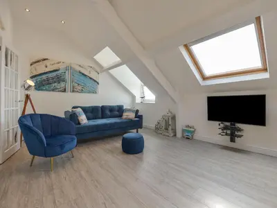 a living room with a blue couch and a flat screen tv at Ocean View in Marazion