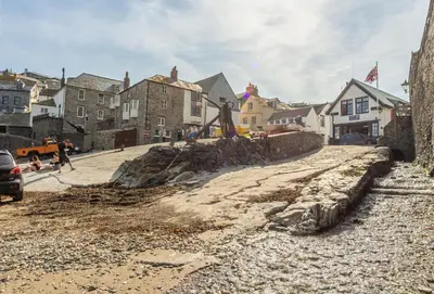 a street in a town with a rock wall at Miss Fishers in Port Isaac