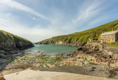 a house on a cliff next to a body of water at Miss Fishers in Port Isaac