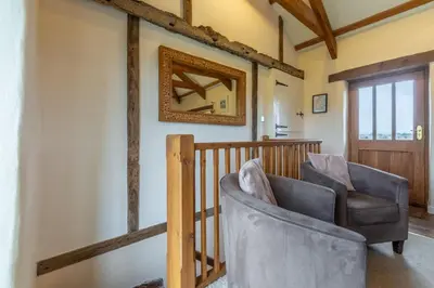 a living room with a chair and a mirror at Spring Barn in Polzeath