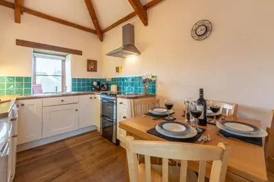 a kitchen with a wooden table and a dining room at Spring Barn in Polzeath