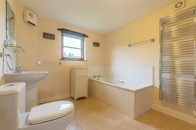 a bathroom with a toilet and a tub and a sink at Spring Barn in Polzeath