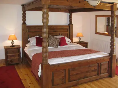 a bedroom with a wooden canopy bed with red pillows at Haye Barton Farm in Liskeard